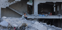 Um menino palestino senta-se entre os escombros de um prédio destruído em Deir al-Balah, no centro da Faixa de Gaza, em 15 de maio de 2023, após um cessar-fogo que encerrou cinco dias de combates mortais entre Israel e o grupo militante palestino Jihad Islâmica.