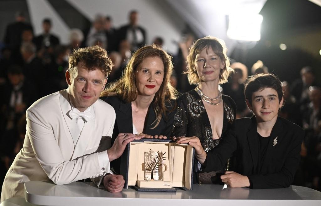 A diretora Justine Triet em foto com os atores Antoine Reinartz, Sandra Hueller e Milo Machado Graner com a Palma de Ouro por "Anatomie d'une Chute"