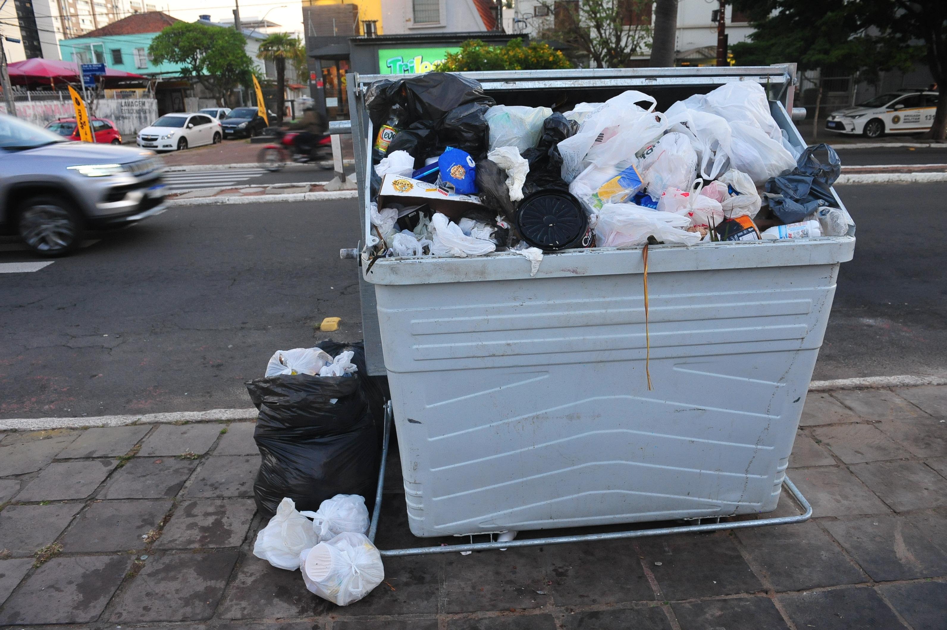 Na rua Jos&eacute; de Alencar, no bairro Menino Deus, o lixo transborda de um dos cont&ecirc;ineres
