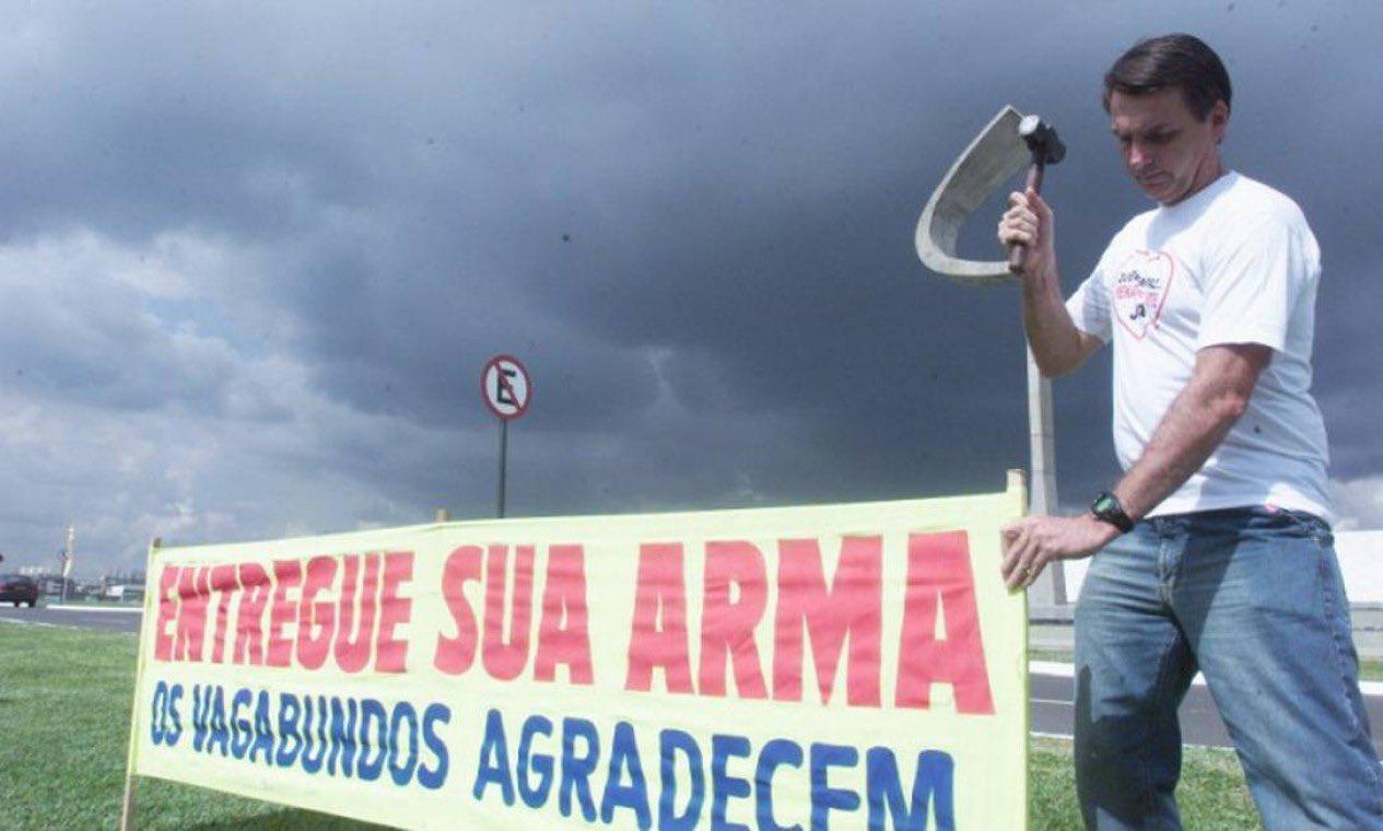 Bolsonaro postou uma foto de 2004 onde aparece colocando uma faixa em um gramado de Bras&iacute;lia com os dizeres "entregue sua arma, os vagabundos agradecem"