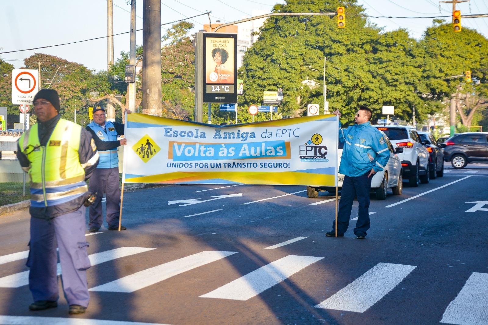 Equipe da EPTC, em conjunto com alunos, auxilia a passagem de pedestres, orienta sobre seguran&ccedil;a e distribui material educativo