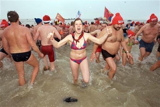 Belgas e turistas entram no mar em dia frio