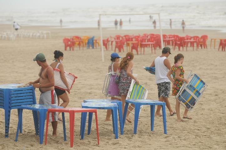Jovens v&atilde;o &agrave; beira da praia, mesmo sem sol para o bronzeamento