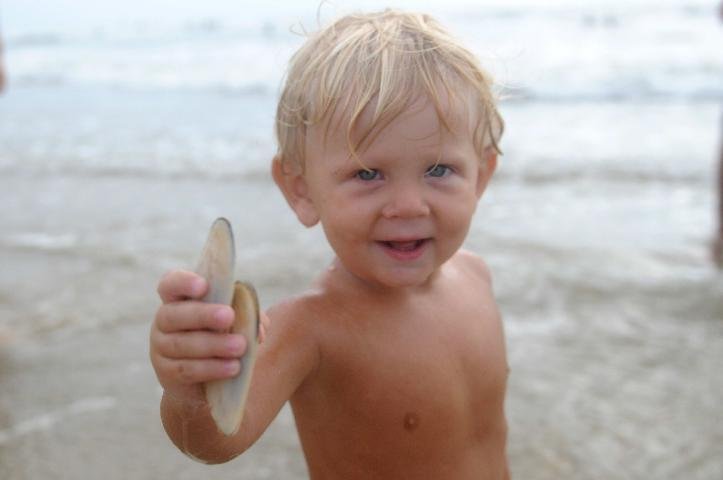 O menino brincava procurando mariscos na areia