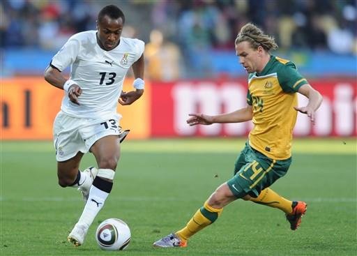 O meio-campista de Gana, Andre Ayew, luta pela bola com o atacante australiano, Brett Holman