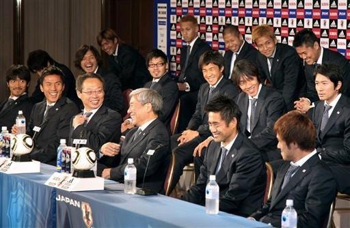 Treinador, Takeshi Okada, fala em uma coletiva de imprensa ap&oacute;s a sua chegada com os membros da equipe em Osaka