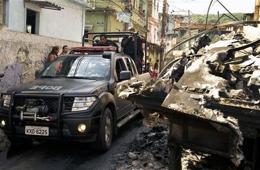 Policiais passam por caminh&atilde;o incendiado na Vila Cruzeiro