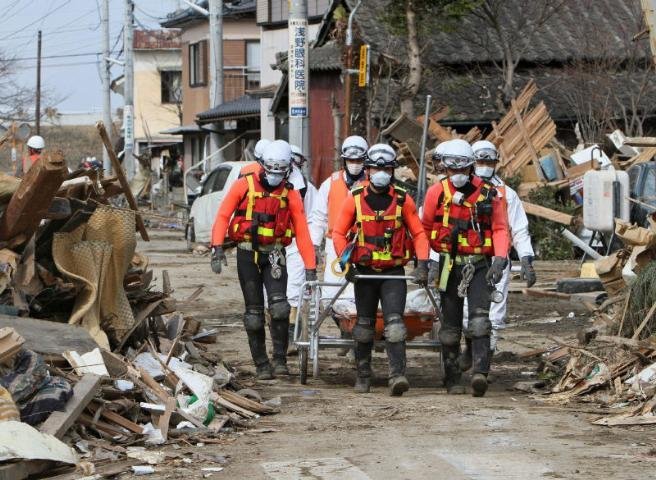Membros da equipe japonesa de resgate transportar um corpo na cidade de Watari
