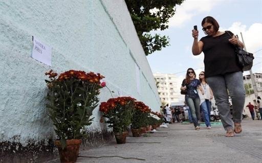 Muro do col&eacute;gio foi transformado em um santu&aacute;rio, com flores, velas, fotos e mensagens