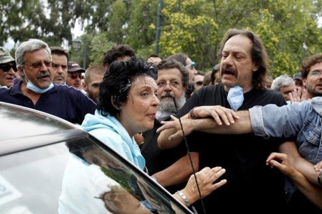Parlamentar grega tenta entrar no carro durante o confronto entre manifestantes e pol&iacute;cia
