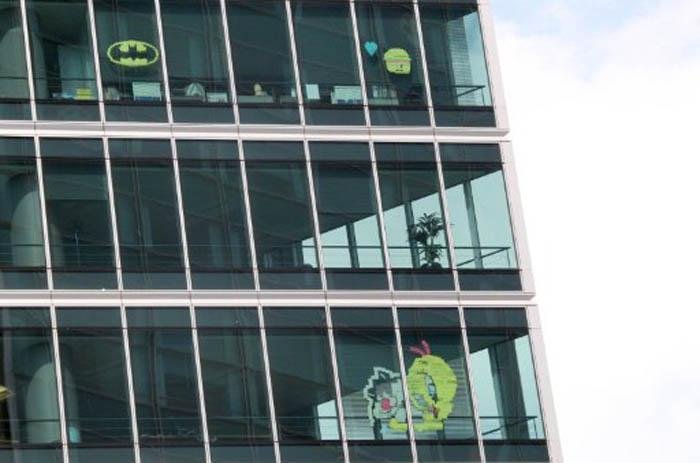 Trabalhadores montam imagens com post its nas janelas dos pr&eacute;dios