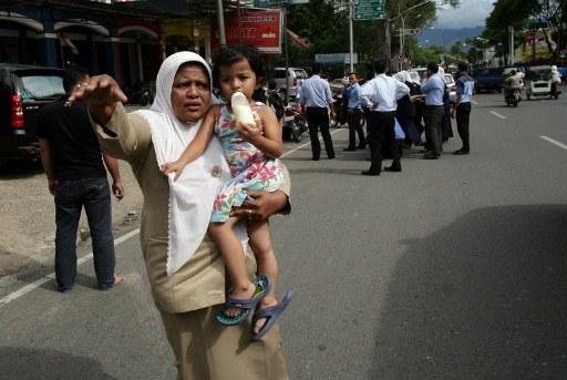 Mulher carrega crian&ccedil;a no colo durante evacua&ccedil;&atilde;o de pr&eacute;dios e casas