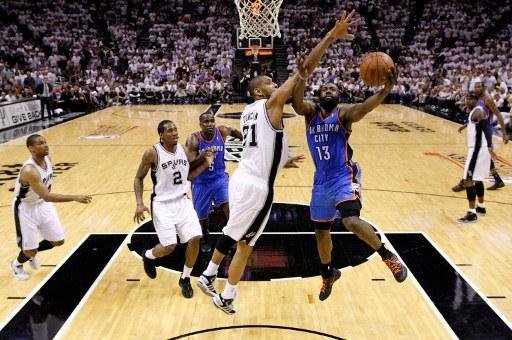 James Harden (&agrave; direita) busca a cesta contra Tim Duncan, do Spurs 