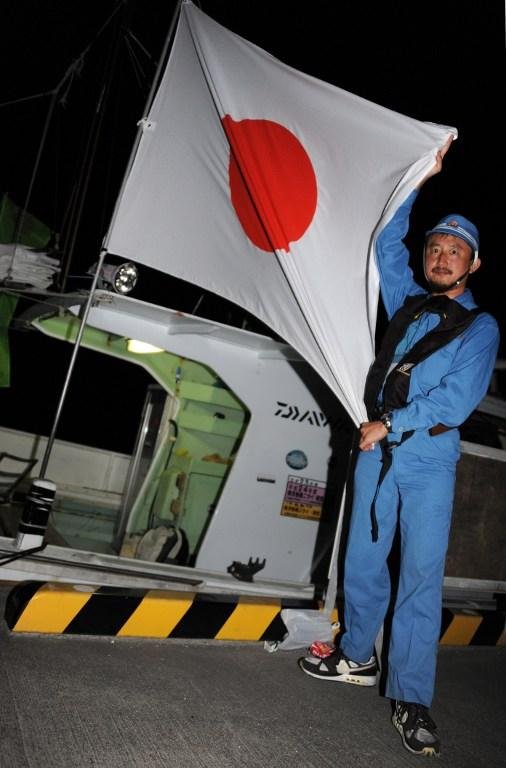 Ativista segura bandeira japonesa antes do embarque da frota