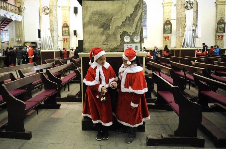 Na China, duas crian&ccedil;as conversam a espera da missa na v&eacute;spera de natal
