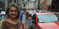 Servidora Giuliana usa o smartphone para chamar táxi