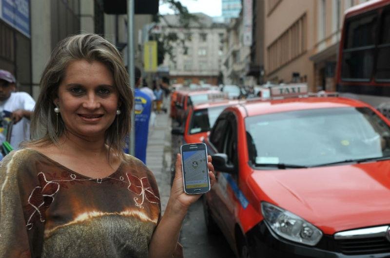 Servidora Giuliana usa o smartphone para chamar t&aacute;xi