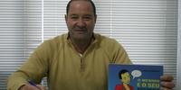 Jorge Luis Martins autografa dois livros durante a Bienal