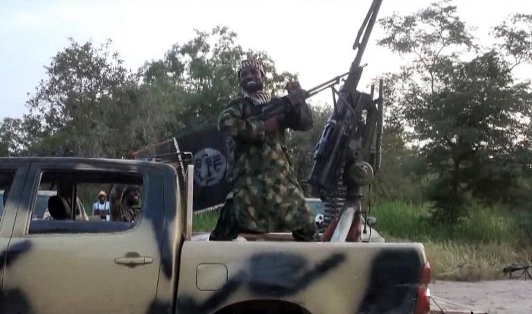 Abubakar Shekau usa roupas de camuflagem e botas e atira para o alto