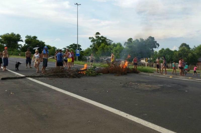 Moradores colocam galhos queimados sobre a pista