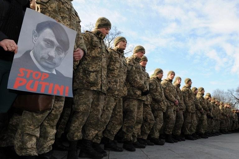 Soldados ucranianos seguram cartaz anti-Putin durante cerim&ocirc;nia em homenagens aos mortos em conflito em Kiev