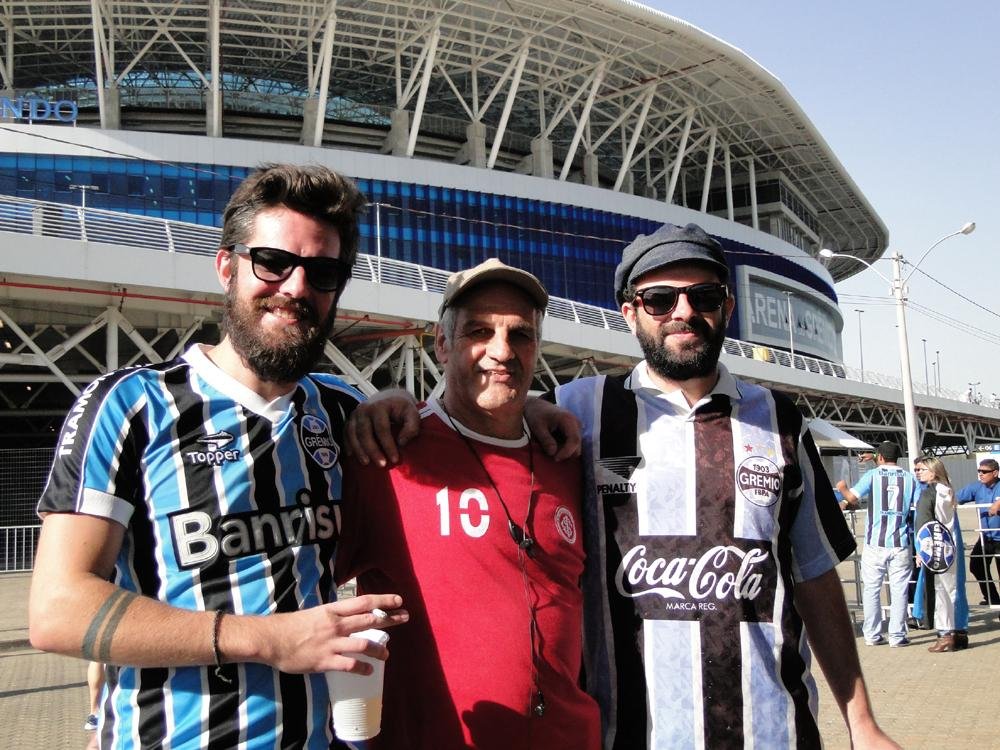 Pai, filho e amigo assistem a jogo juntos