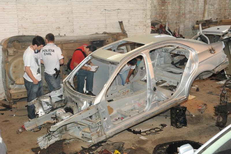 Policiais examinam carca&ccedil;a de autom&oacute;vel em desmanche ilegal em Porto Alegre