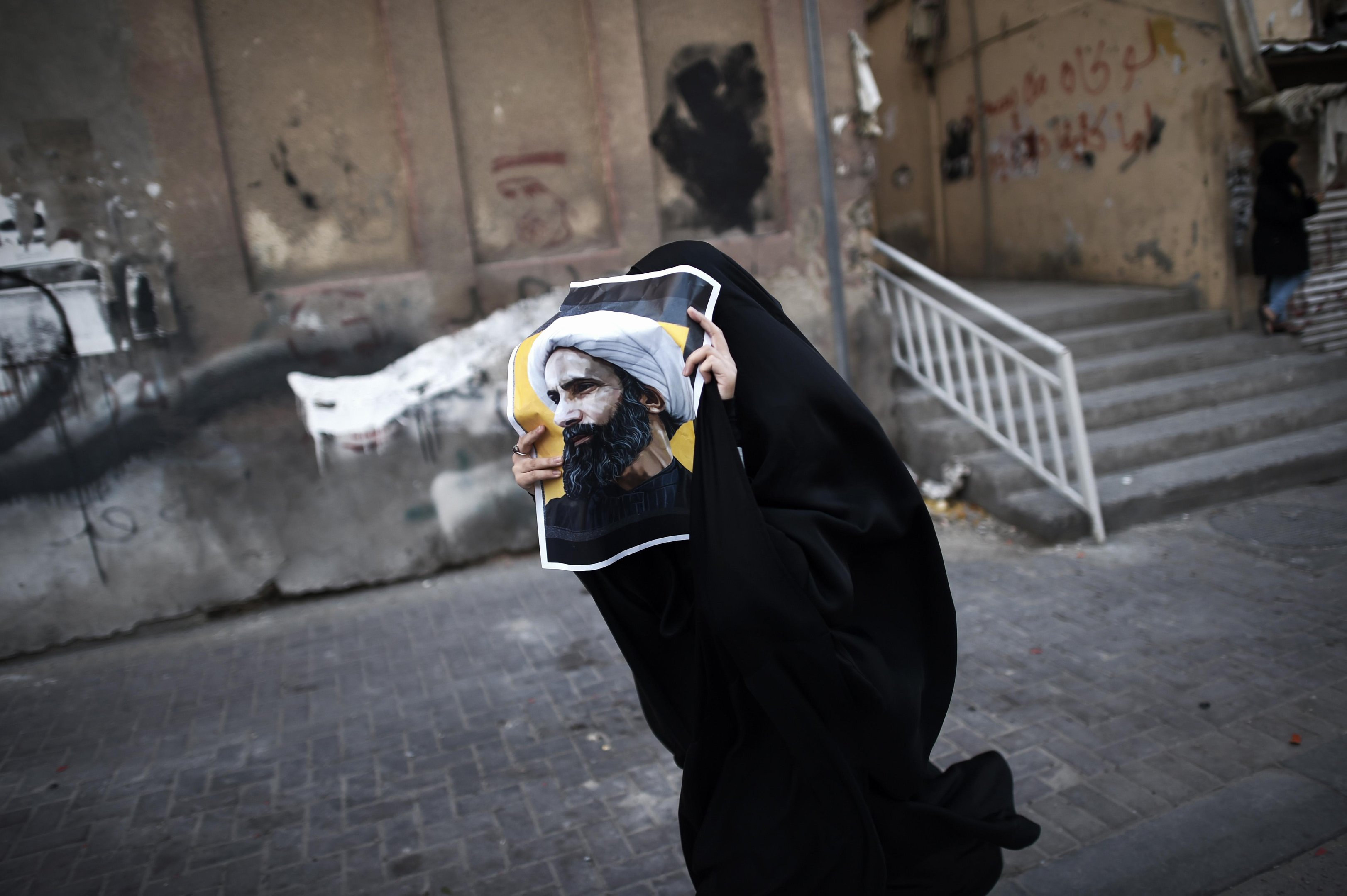 Mulher corre com poster de cl&eacute;rigo executado no Bahrein