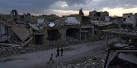 Crianças sírias caminhando pelas construções danificadas em Douma