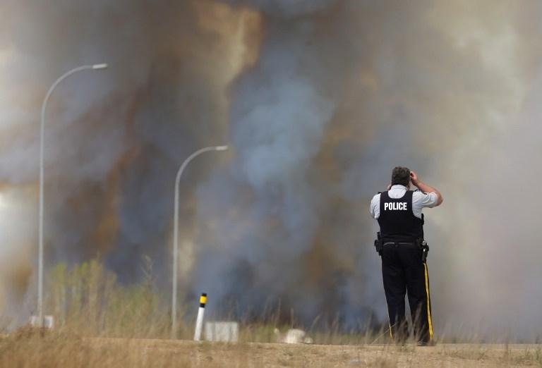 Policial observa inc&ecirc;ndio ao longo da estrada perto de Fort McMurray