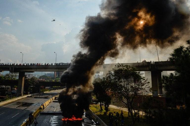 Manifestantes com os rostos cobertos ou encapuzados jogaram gasolina na autoestrada e atearam fogo aos caminh&otilde;es, que estavam estacionados, sem que a pol&iacute;cia reagisse de imediato