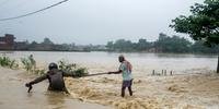 Moradores nepalenses tentam atravessar área inundada