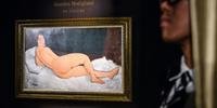 Pintura mostra uma mulher nua deitada do lado esquerdo e olhando para o público