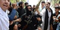 Militantes afegãos do Talibã carregam um foguete enquanto observam moradores que saem para a rua para celebrar o cessar-fogo