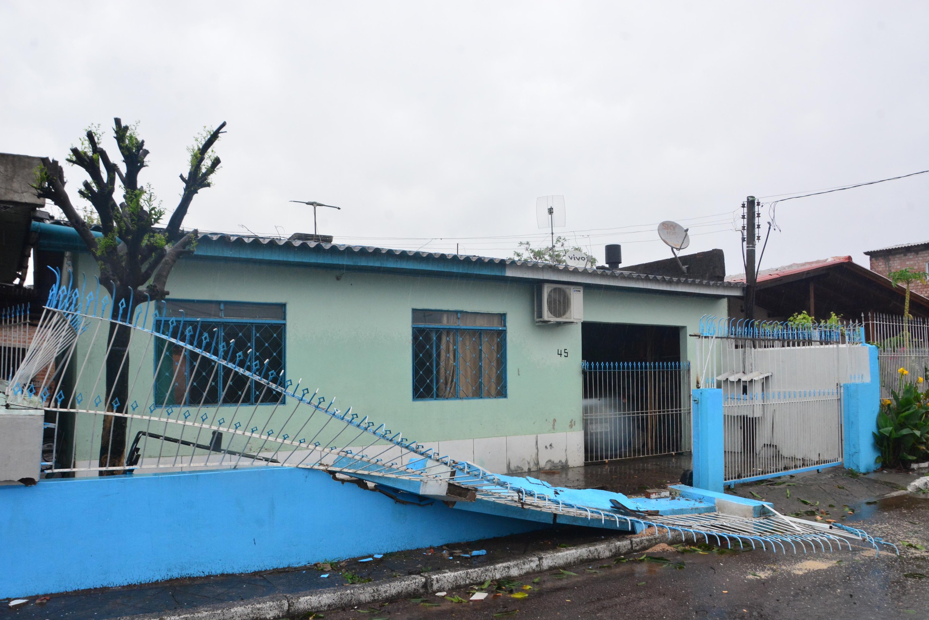 Na rua Veneza, na zona Norte de Porto Alegre, uma &aacute;rvore caiu sobre o muro de uma resid&ecirc;ncia