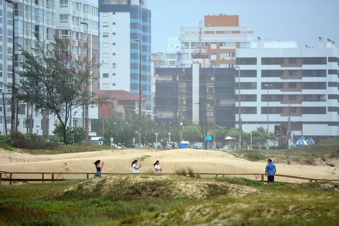 Apesar do mau tempo, veranistas aproveitam dia para caminhar pela praia