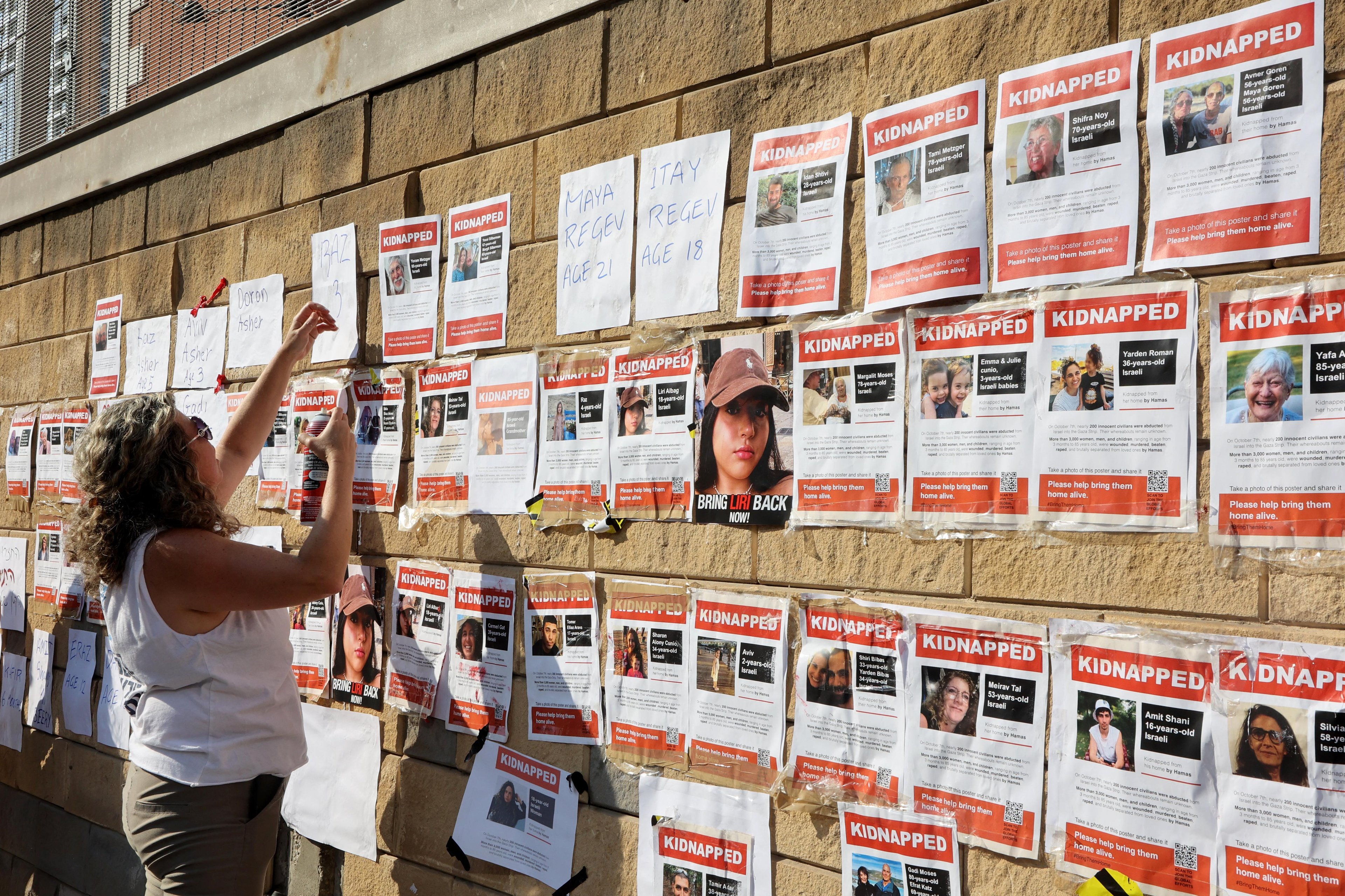 Parentes de ref&eacute;ns protestam contra demora do Estado em agir colando fotos de seus parentes sequentrados no muro de uma base militar, em Israel