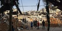 Palestinos procuram por sobreviventes entre os escombros de edifício em Rafah, no sul de Gaza