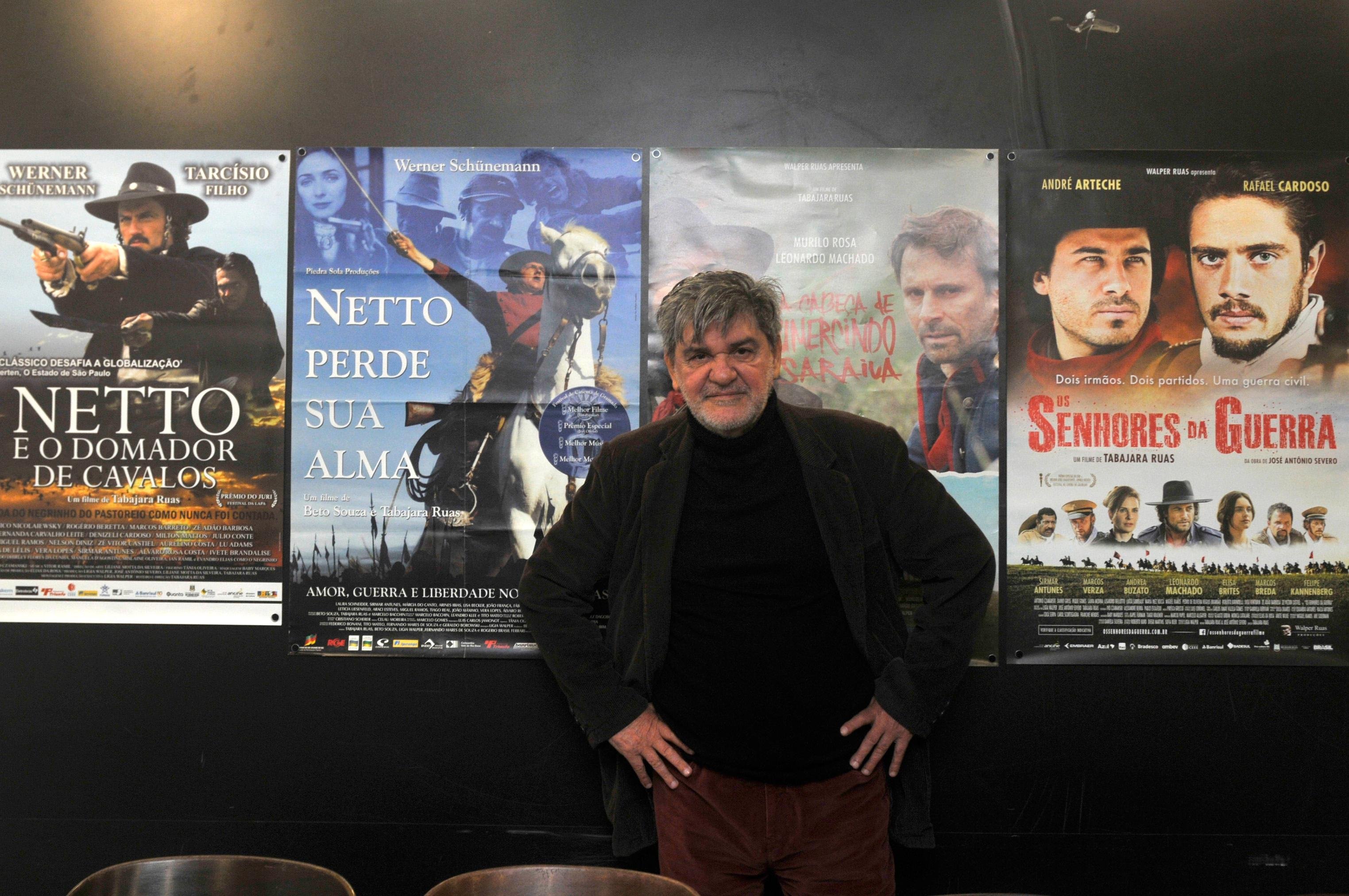 Tabajara Ruas em frente aos cartazes de seus filmes em mostra na CCMQ