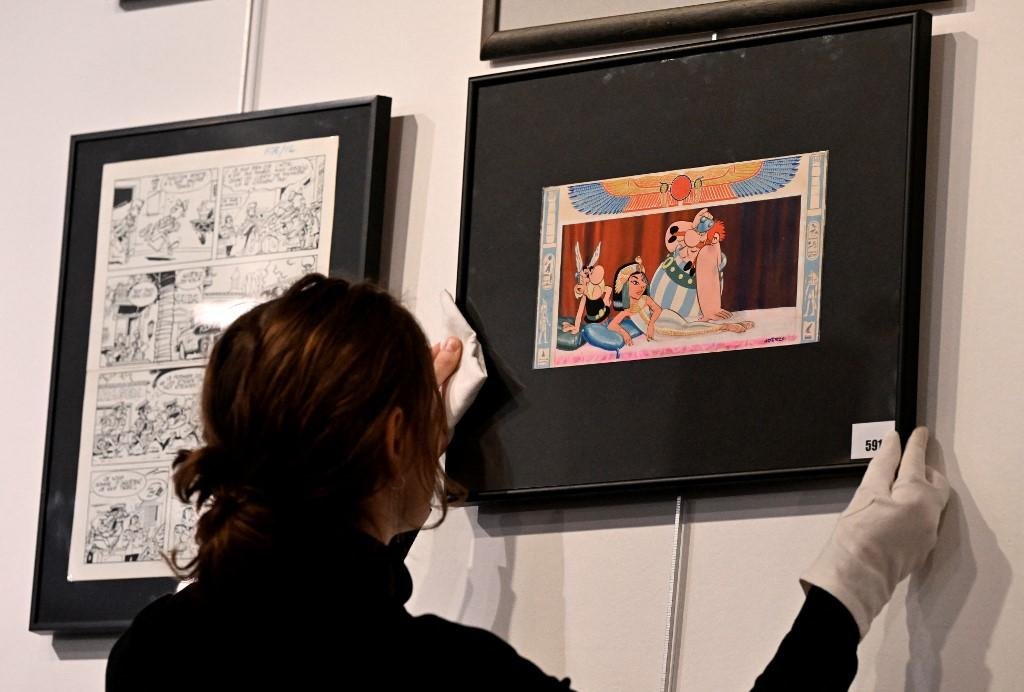 Albert Uderzo desenhou a rainha eg&iacute;pcia reclinada e os dois her&oacute;is gauleses, Ast&eacute;rix e Ob&eacute;lix