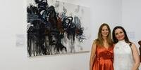 Curadora Denise Giacomoni (E) e a artista Lu Gaudenzi e sua obra na mostra Babel