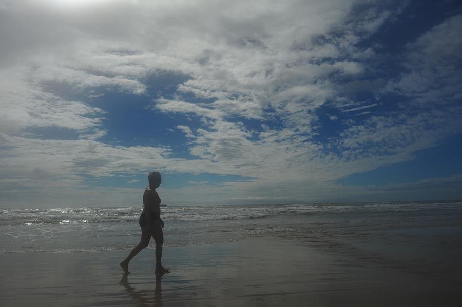 Com c&eacute;u nublado ap&oacute;s a chuva, veranistas aproveitam a beira da praia em Tramanda&iacute;
