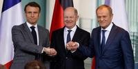 Presidente francês Emmanuel Macron, o chanceler alemão Olaf Scholz e o primeiro-ministro polaco Donald Tusk dão-se as mãos numa conferência de imprensa na Chancelaria em Berlim