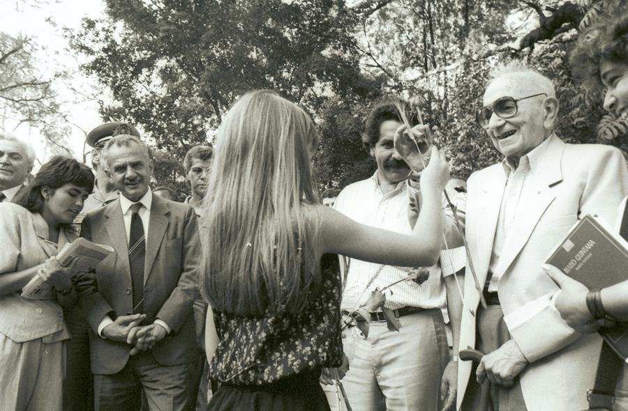 Mario Quintana recebe rosa de uma leitora infantil quando foi patrono da Feira do Livro, em 1985, diante de pol&iacute;ticos como Pedro Simon e Ol&iacute;vio Dutra
