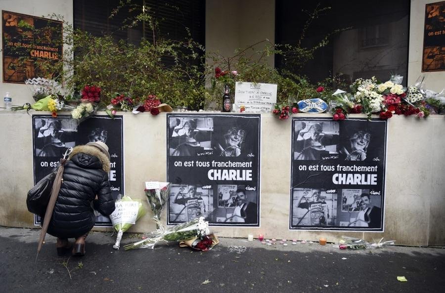 Mulher presta homenagem aos mortos do atentado  e coloca flores perto dos escrit&oacute;rios do jornal sat&iacute;rico franc&ecirc;s Charlie Hebdo em Paris em 8 de janeiro de 2015