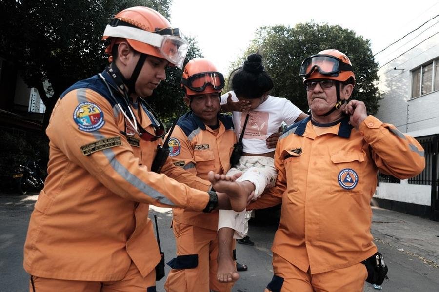 Membros da Defesa Civil ajudam uma crian&ccedil;a em um dos locais de conflito armado