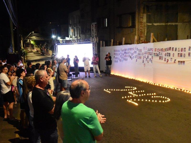 Em uma parede branca foram colocadas fotos e no ch&atilde;o, velas eletr&ocirc;nicas formaram o n&uacute;mero 242, lembrando as v&iacute;timas daquele 27 de janeiro