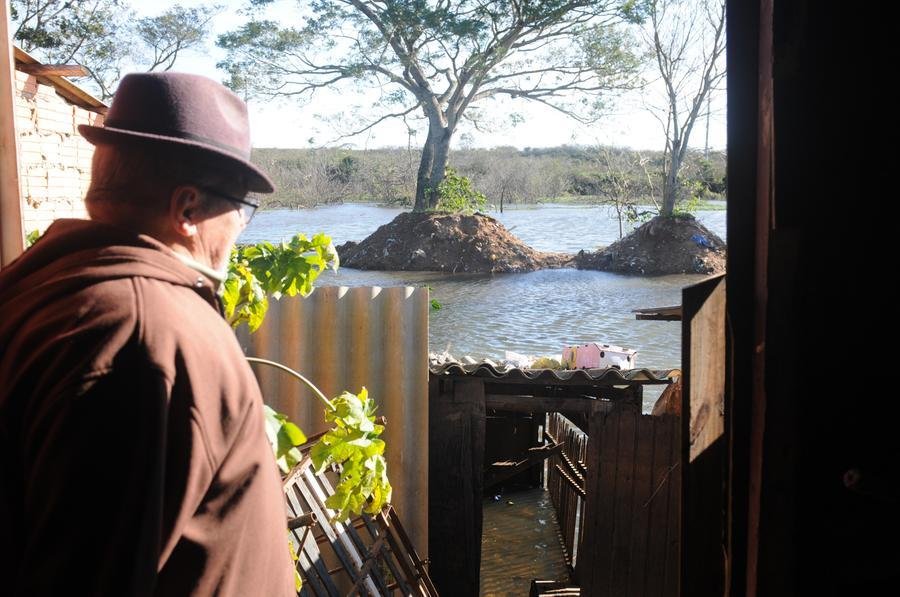 Eri Francisco Costa Israel, de 75 anos, observa o avan&ccedil;o das &aacute;guas nos fundos de sua casa