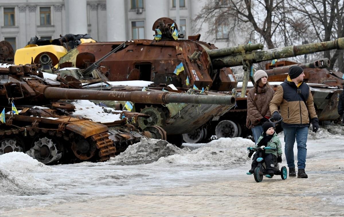 Em Kiev, pessoas passeiam ao lado de um tanque russo destru&iacute;do