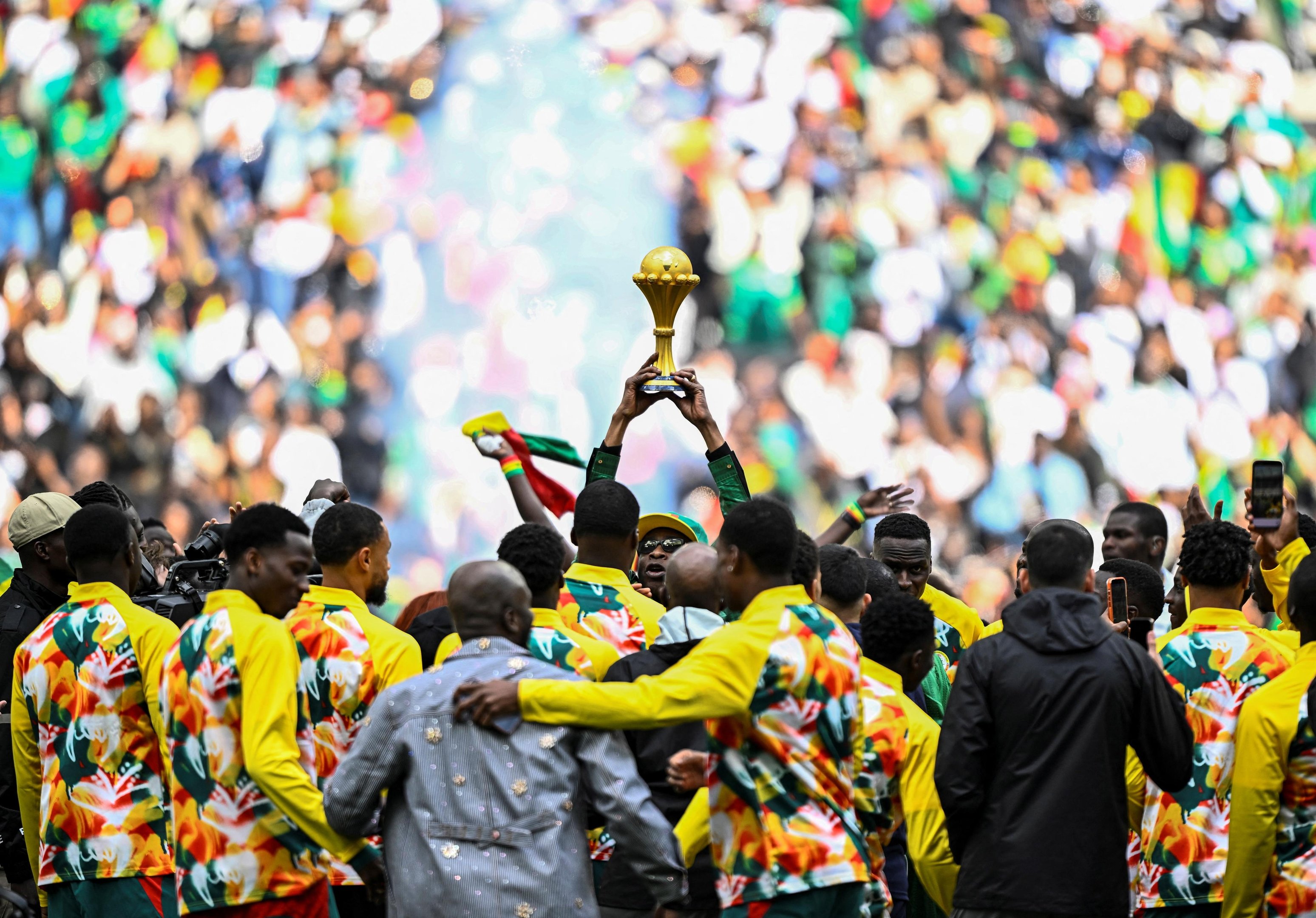 M&uacute;sico senegal&ecirc;s Youssou N'Dour segura o trof&eacute;u da Copa das Na&ccedil;&otilde;es Africanas enquanto os jogadores do Senegal se re&uacute;nem ao seu redor antes da partida amistosa entre Senegal e Peru, em Paris